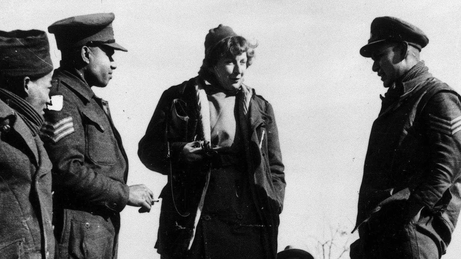 Black and white image of Martha Gellhorn standing with British Army soldiers
